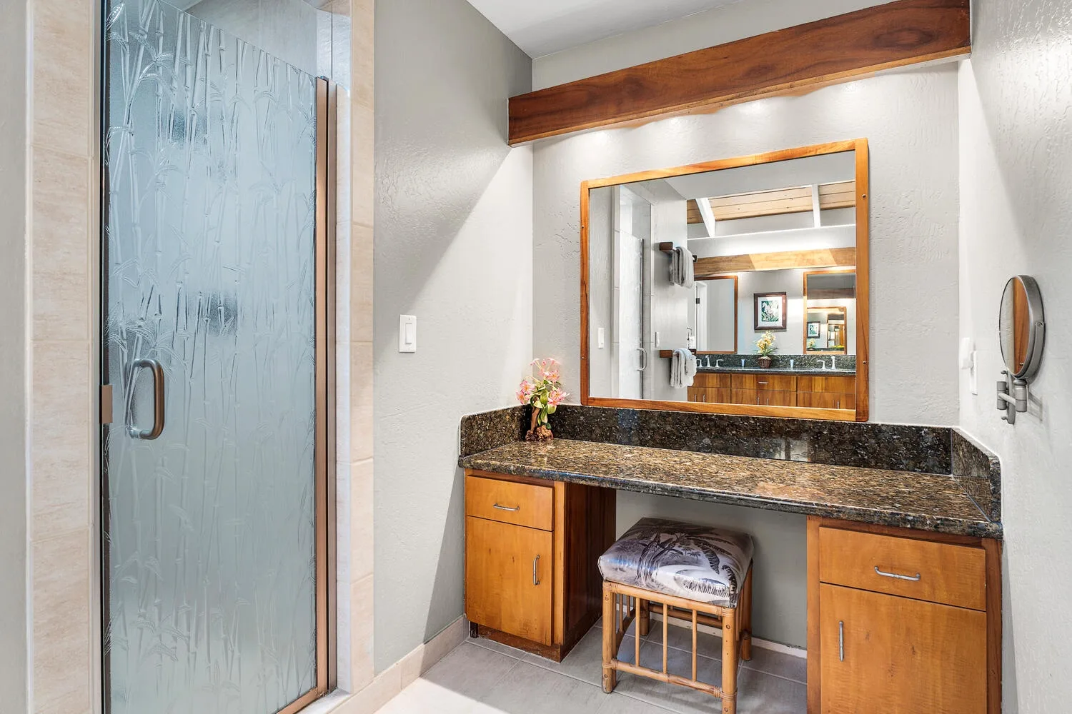 A bathroom vanity with a wide mirror and a frosted glass shower.