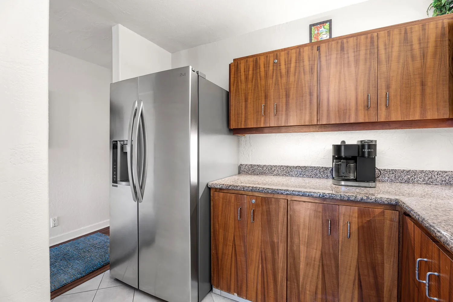 A kitchen area with wooden cabinets, a refrigerator, and a coffee maker.