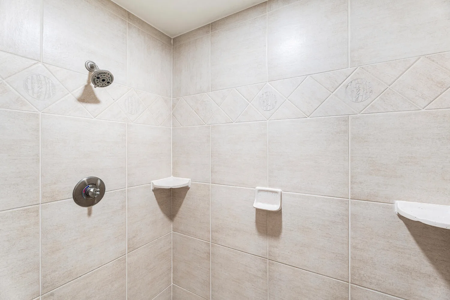 A tiled shower area with a wall-mounted showerhead and fixtures.