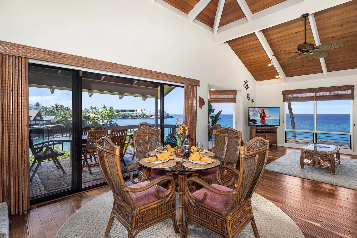 A dining area with wicker seating and large windows overlooking the ocean.