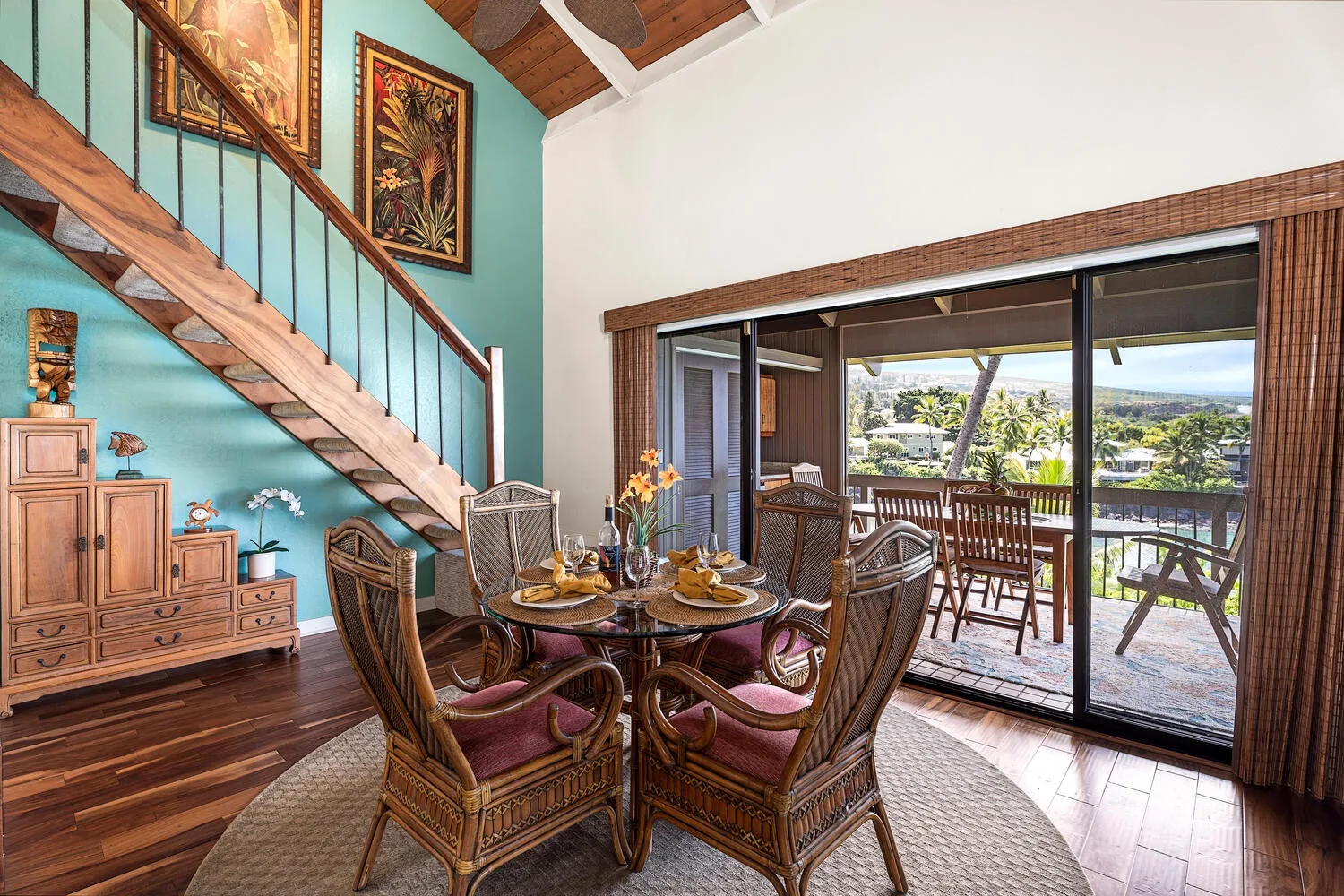 A dining area with wicker seating sits beside sliding glass doors opening onto a balcony.
