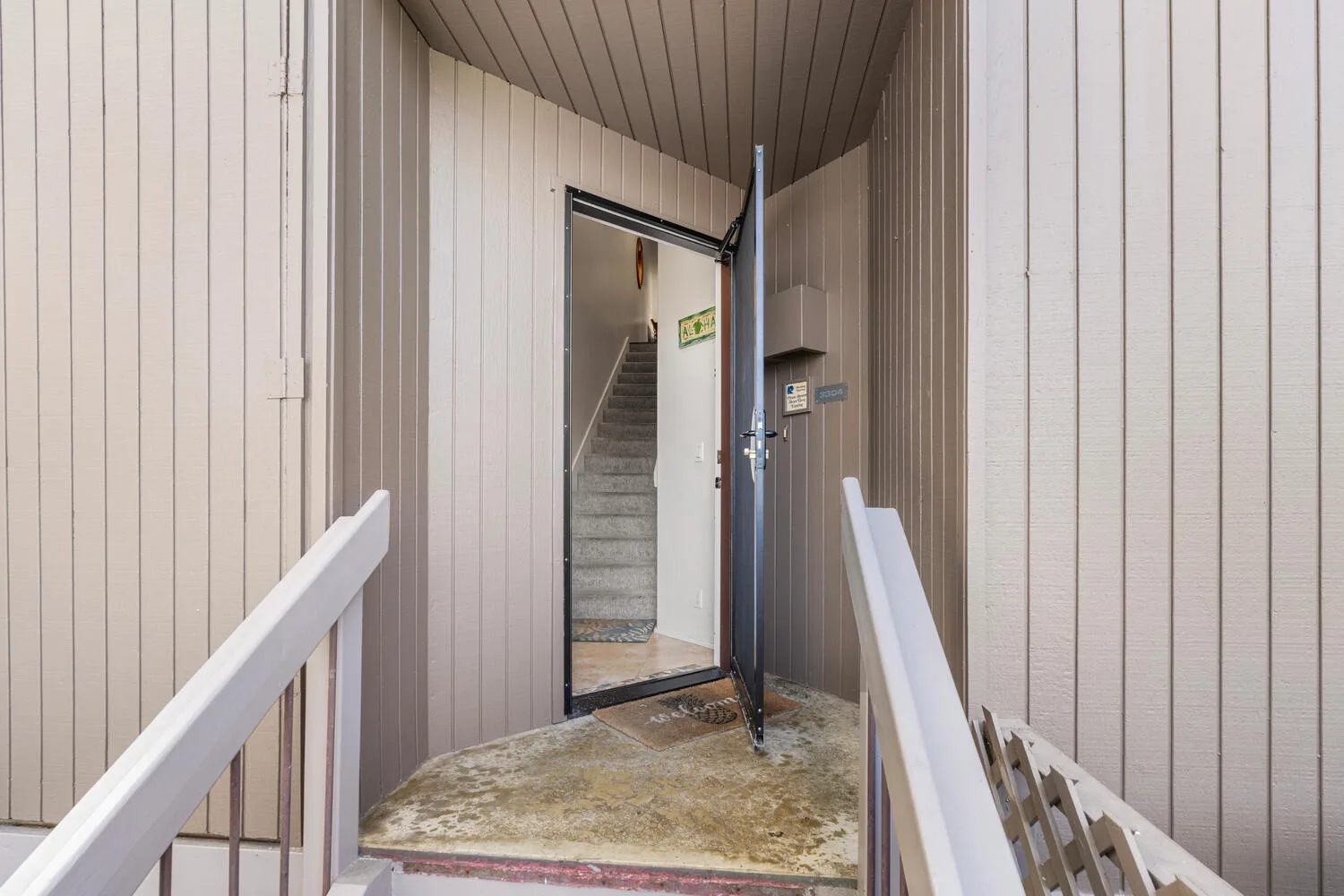 An exterior entryway with an open door and a staircase visible inside.