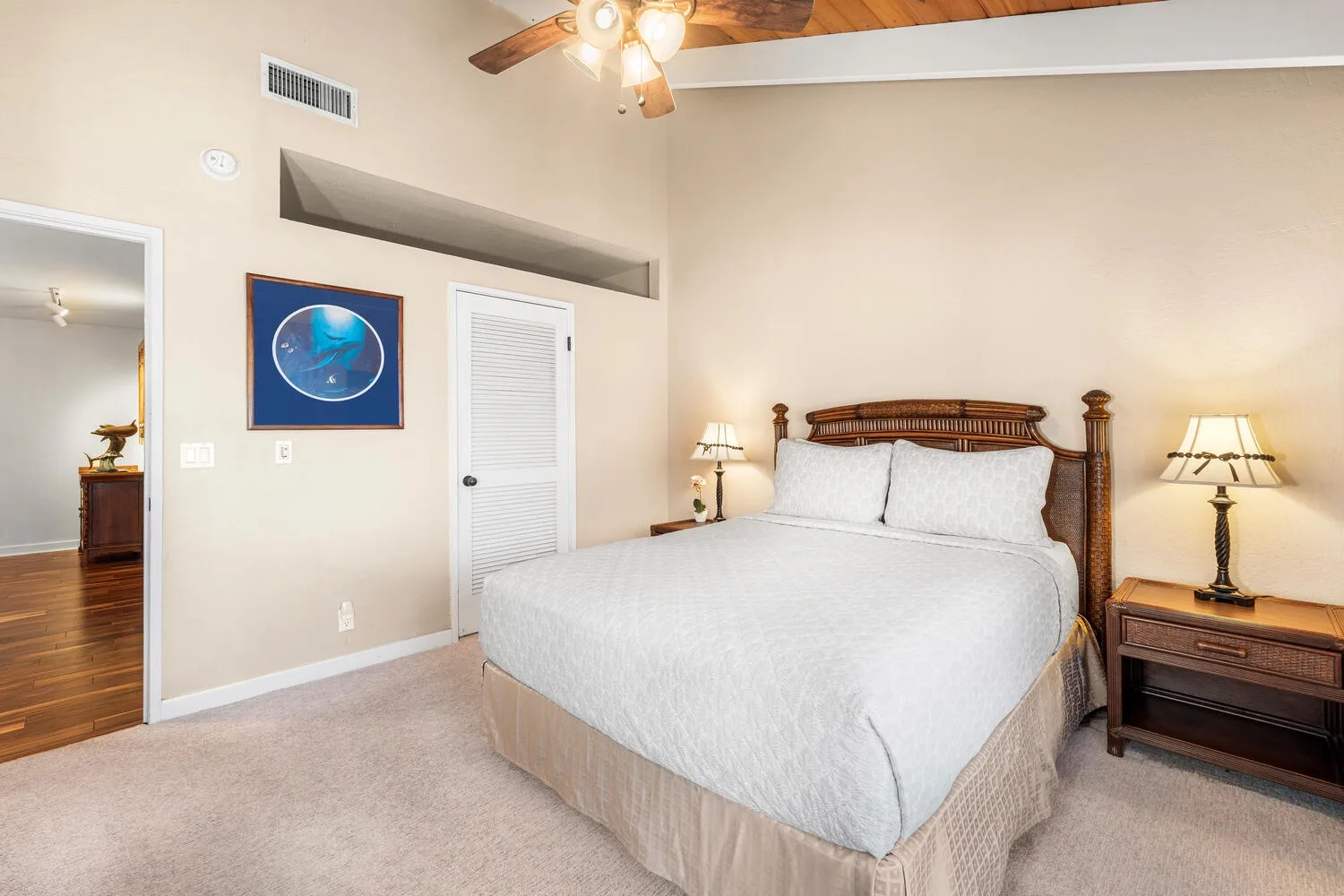 A bedroom with a bed, bedside tables, and a ceiling fan.