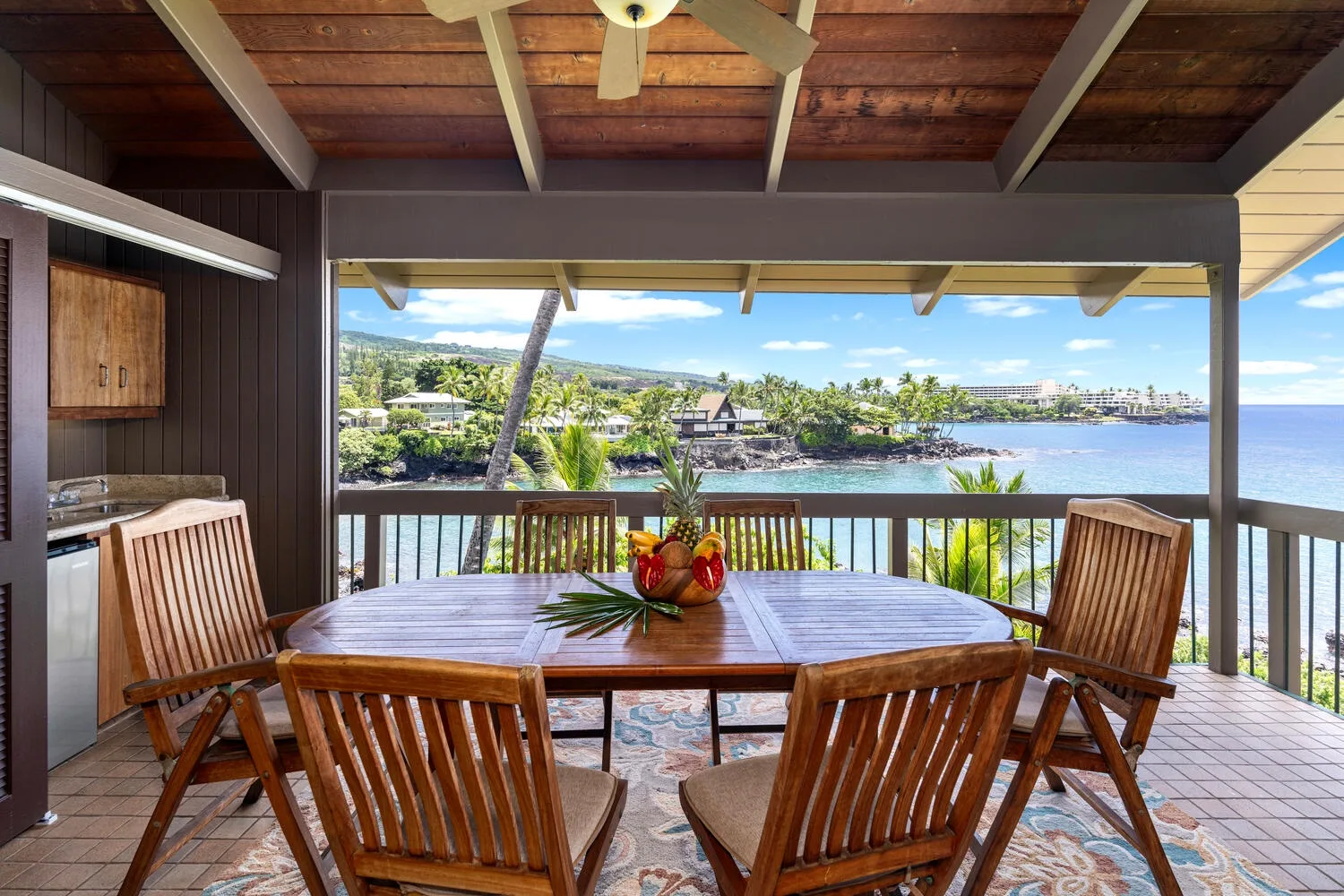 A covered dining area opens onto a view of the water and shoreline.