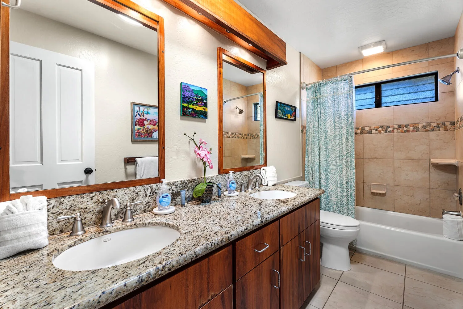 A bathroom vanity with sinks faces a tiled bathtub and shower.