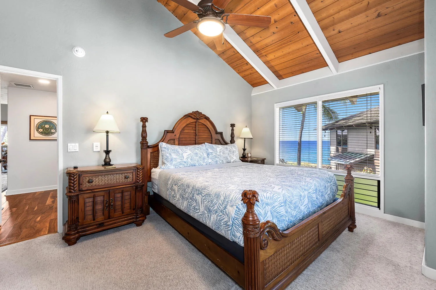 A bedroom with a carved wooden bed, a dresser, and a vaulted wood ceiling.