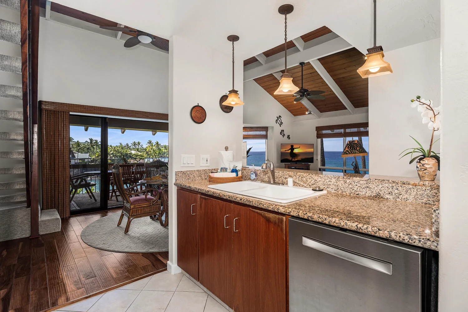A kitchen counter with a sink overlooks a living area and ocean view.