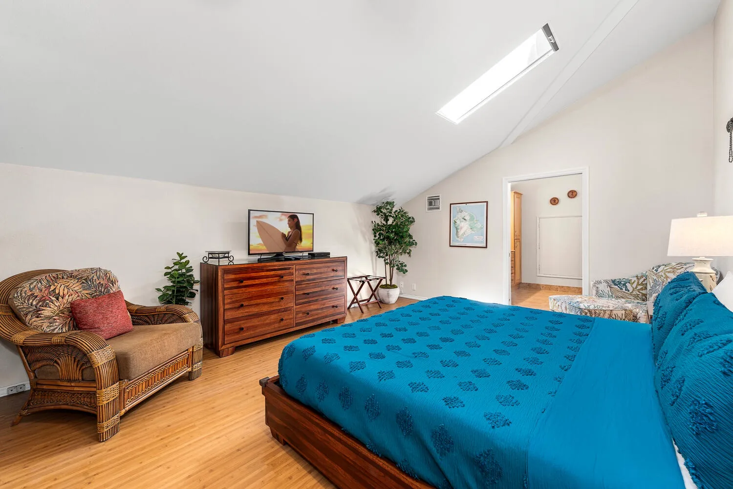 A bedroom with a blue bed, wooden dresser, and armchair.