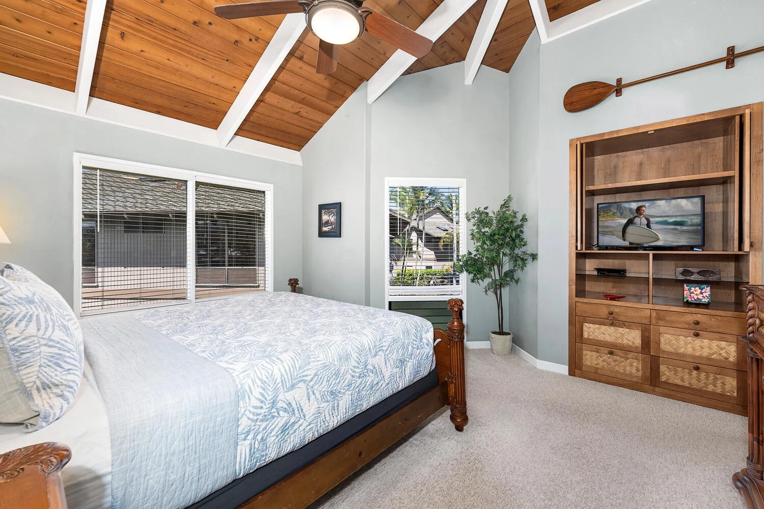 A bedroom with a large bed, a vaulted wood ceiling, and built-in shelving.