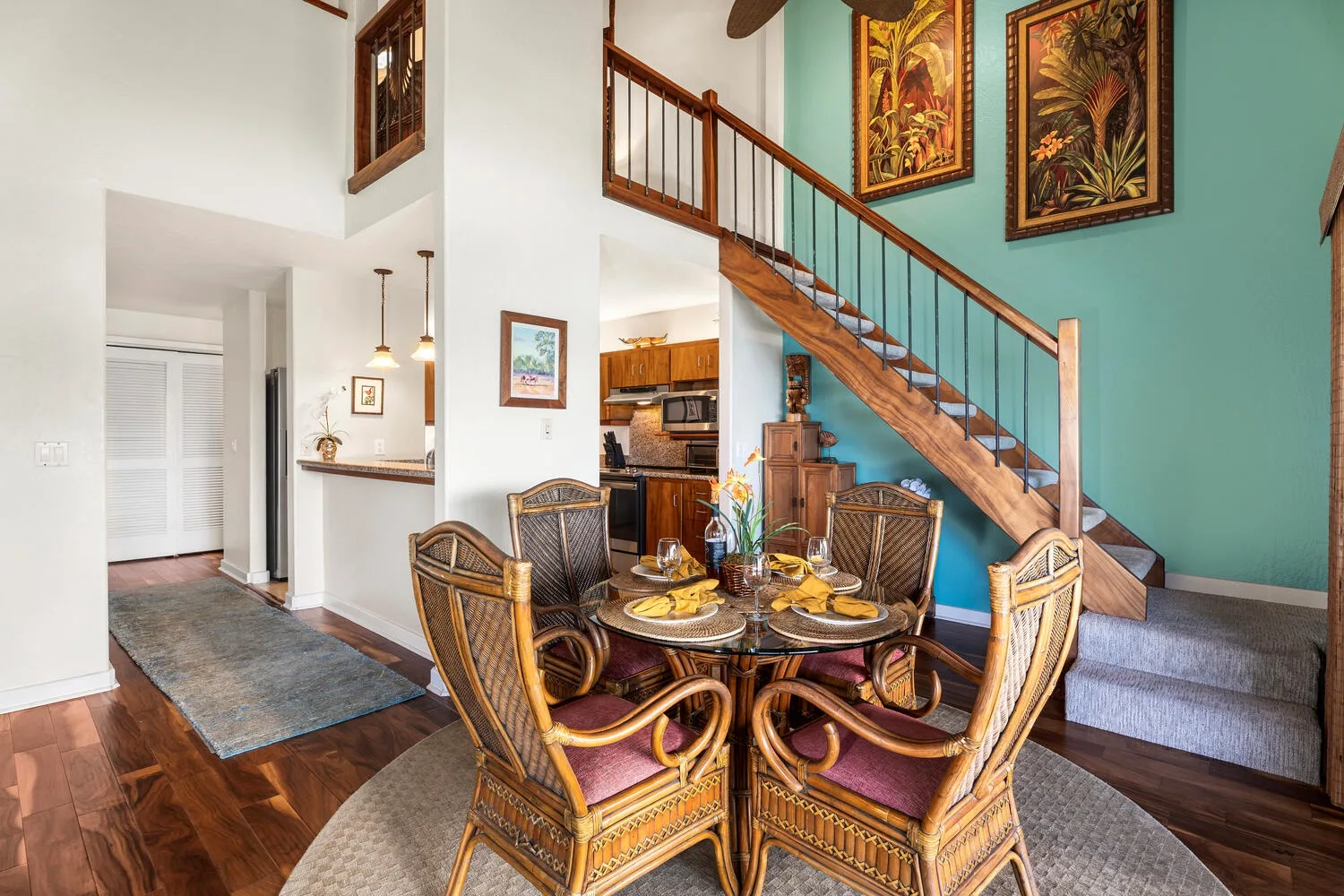A dining area with a round table and wicker seating beneath a staircase.