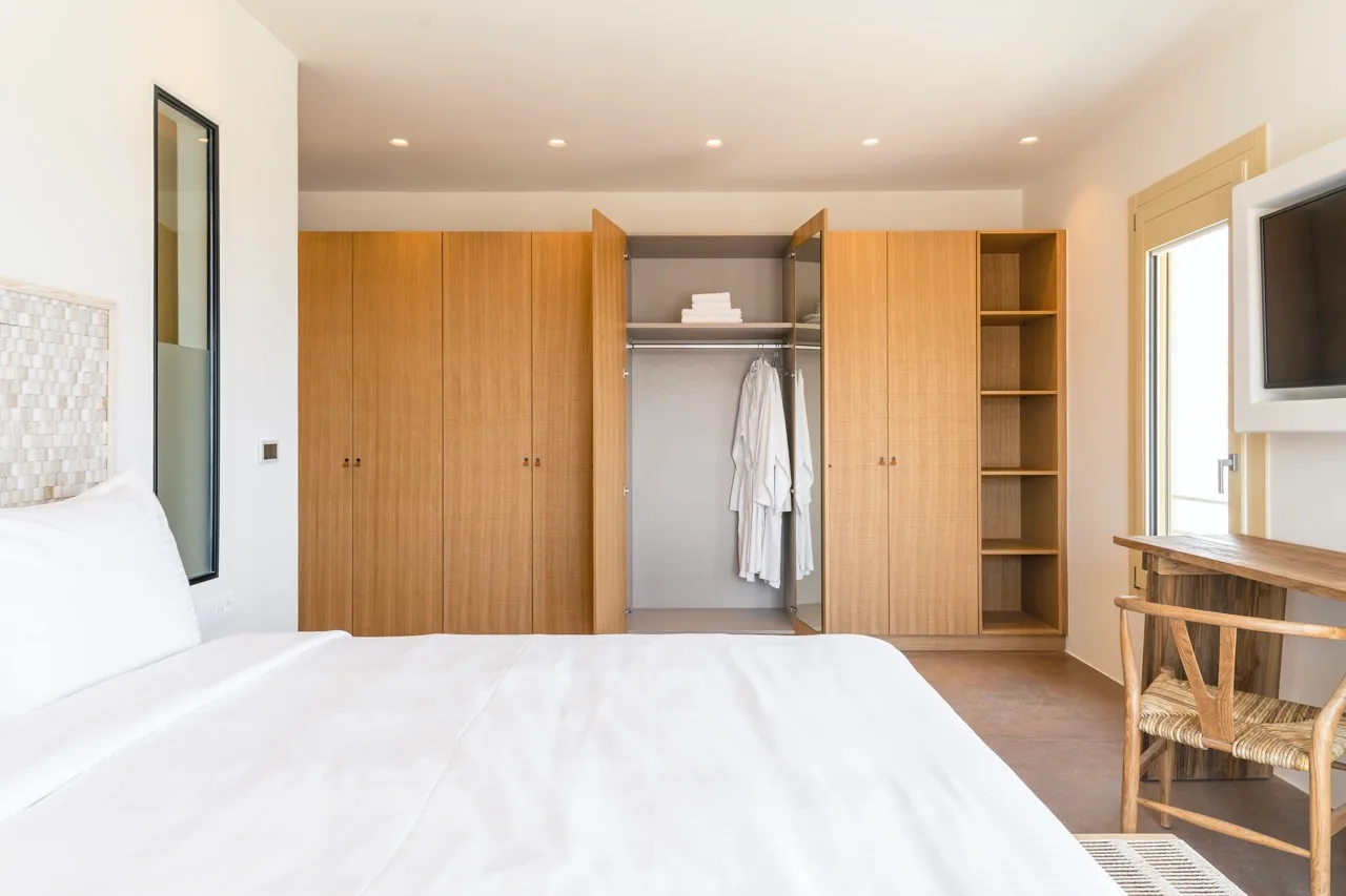A bright bedroom with a bed and built-in wardrobes along the back wall.
