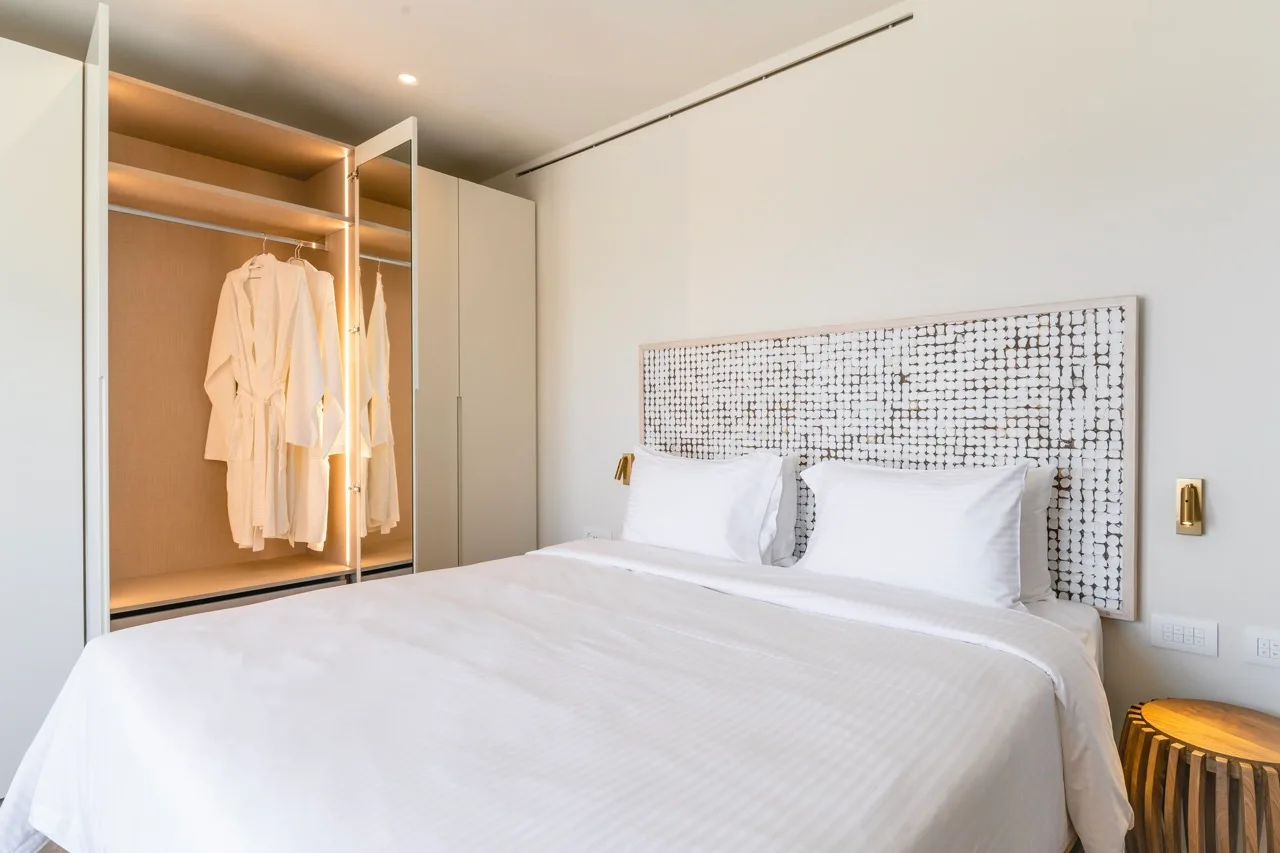 A bedroom with a neatly made bed and an open wardrobe.