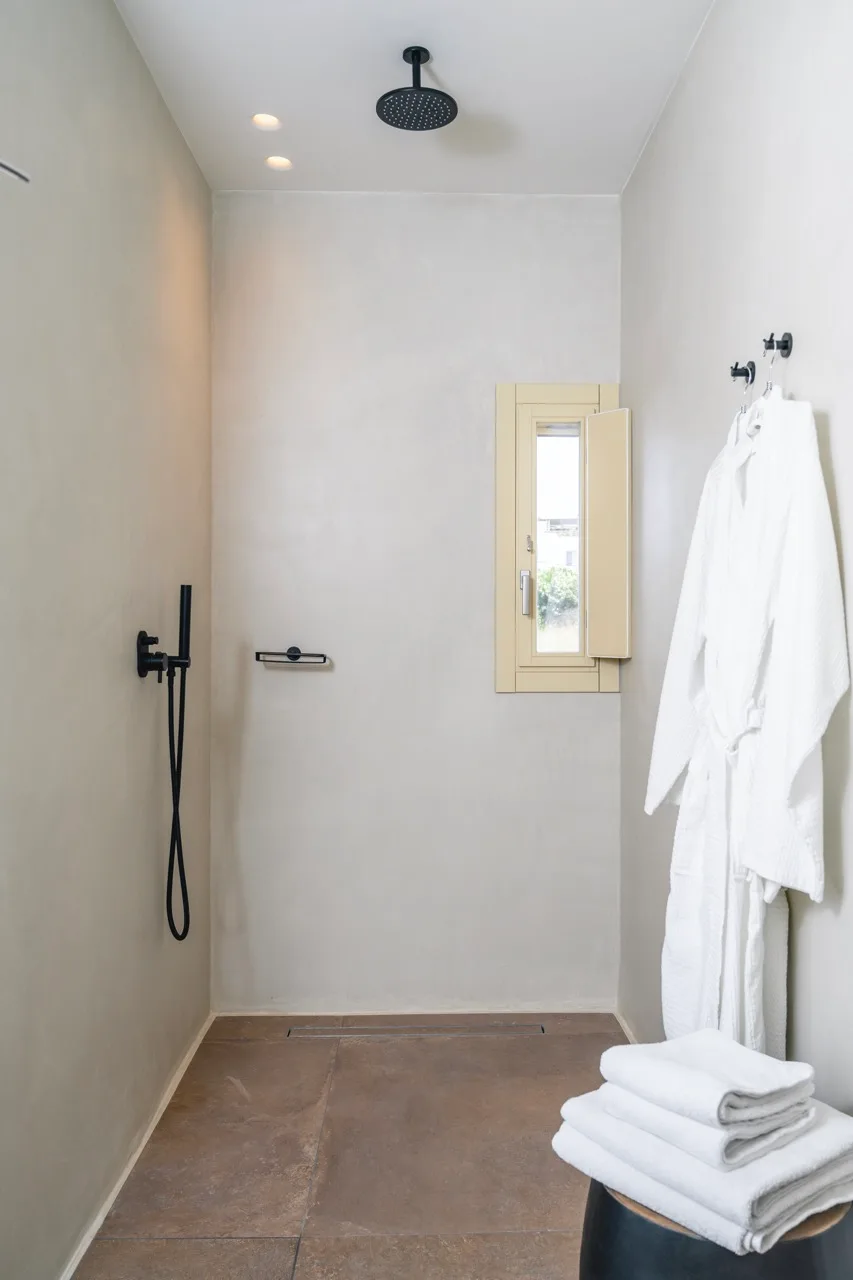 A walk-in shower with a wall-mounted showerhead and folded towels.