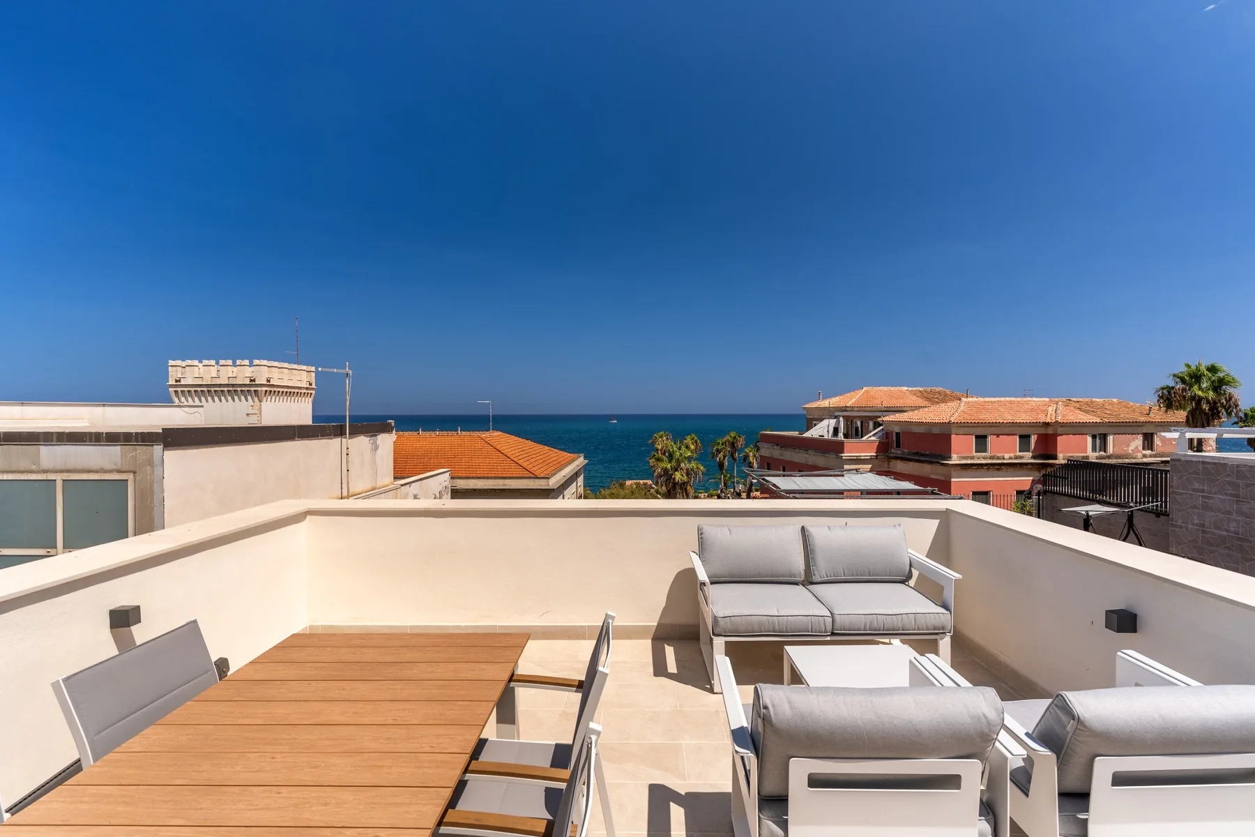 A rooftop terrace with outdoor seating and a view of the sea.