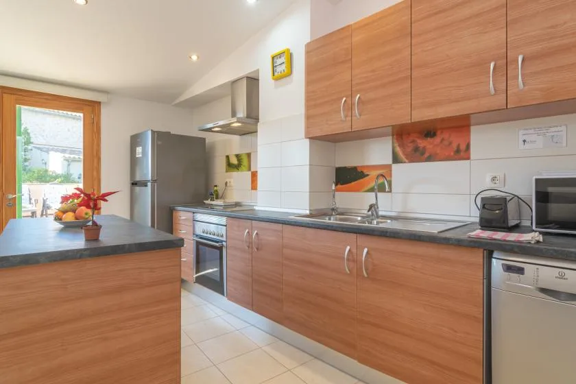 A modern kitchen with wood cabinets, a countertop, and stainless steel appliances.