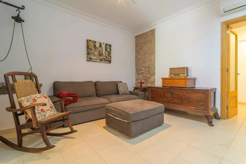 A living room with a sofa, rocking chair, and wooden cabinet.