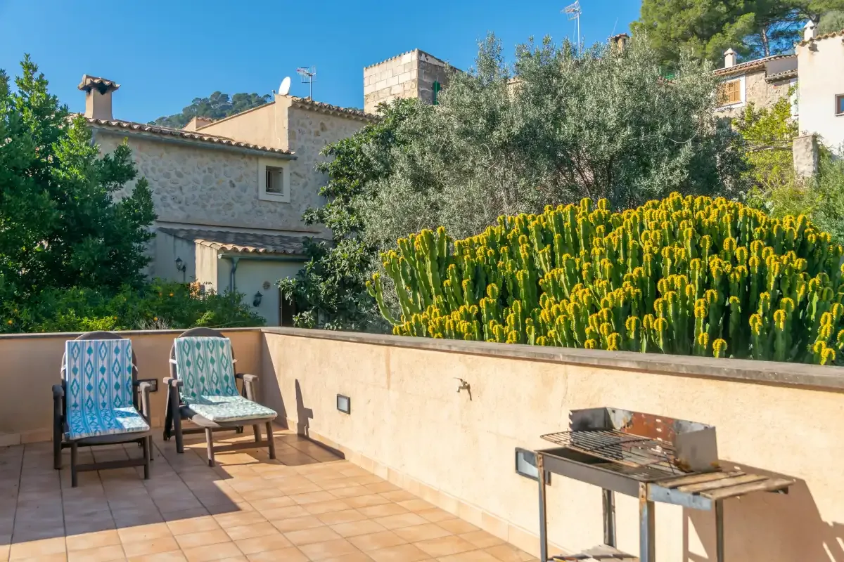 A sunny outdoor terrace with seating and a barbecue grill.