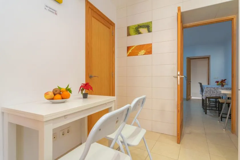 A bright tiled dining area with a white table and an open doorway.
