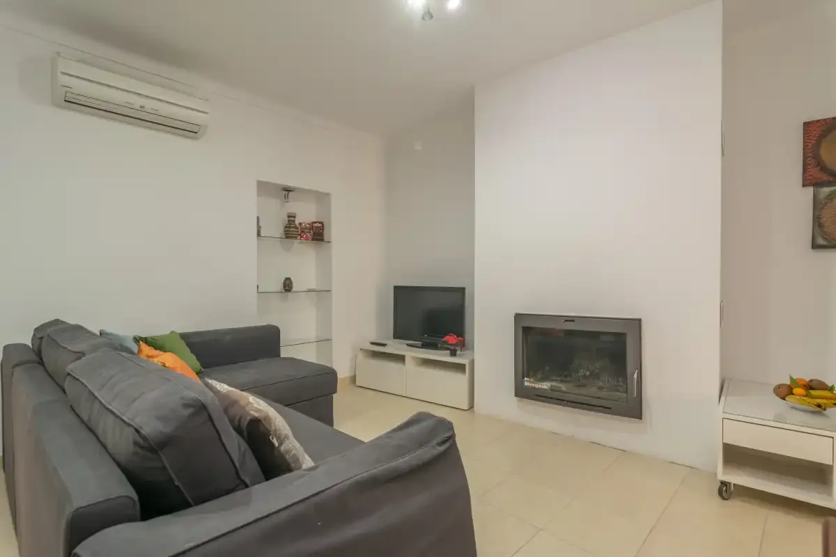 A living room with gray seating, a television, and a fireplace.