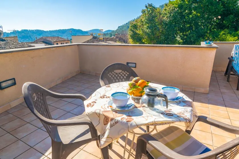 A sunny tiled terrace with a table set with cups and fruit.