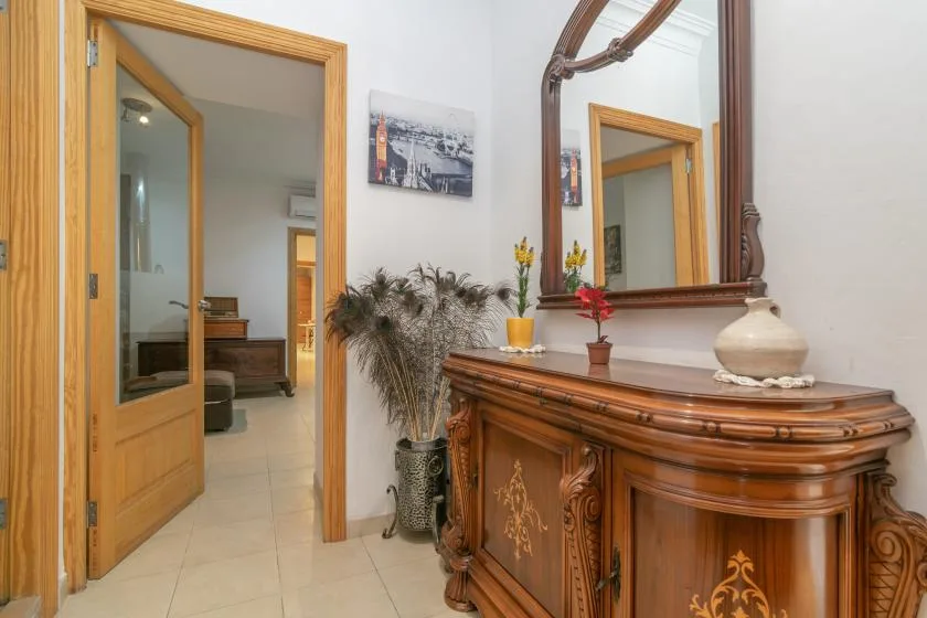 A hallway with a carved wooden console table and a large wall mirror.