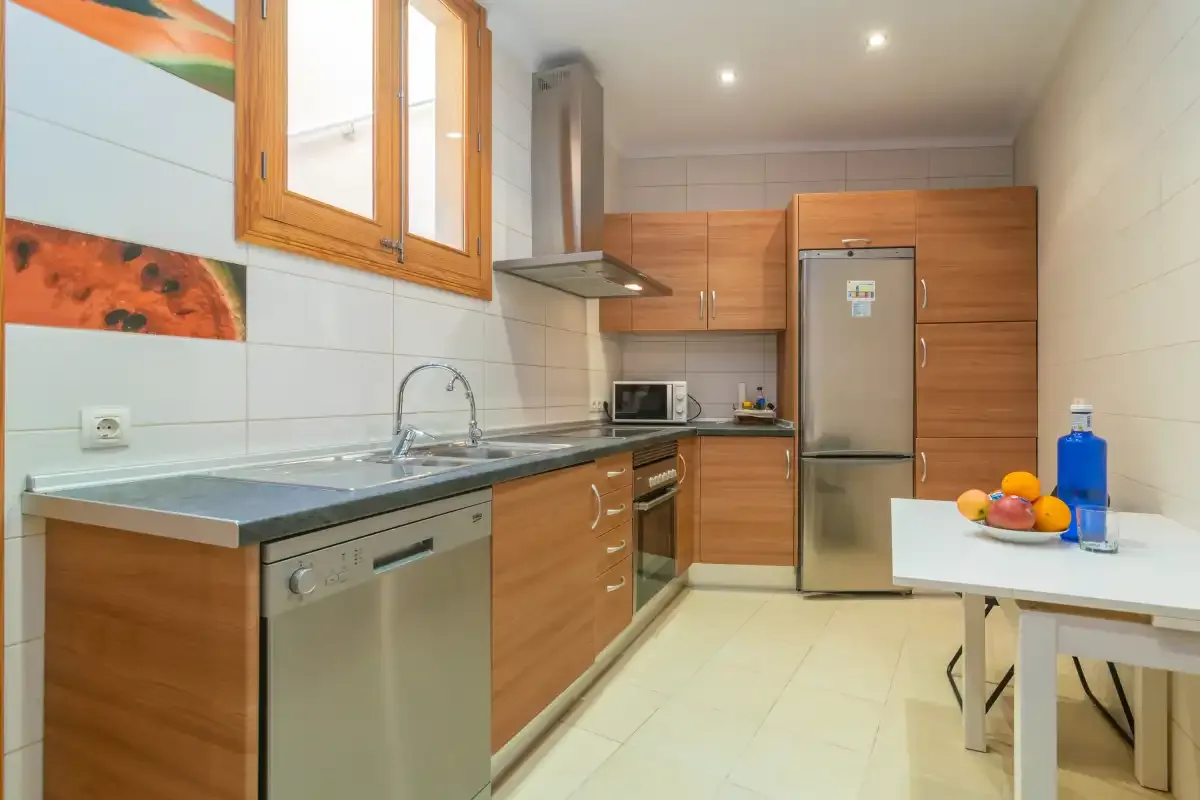 A modern kitchen with wooden cabinets, a countertop, and a refrigerator.
