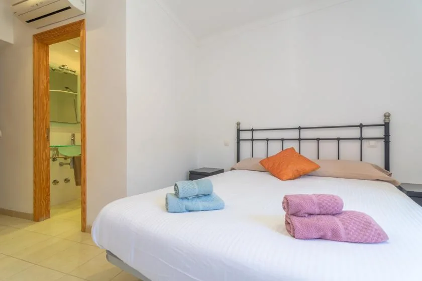 A bedroom with a neatly made bed and folded towels.