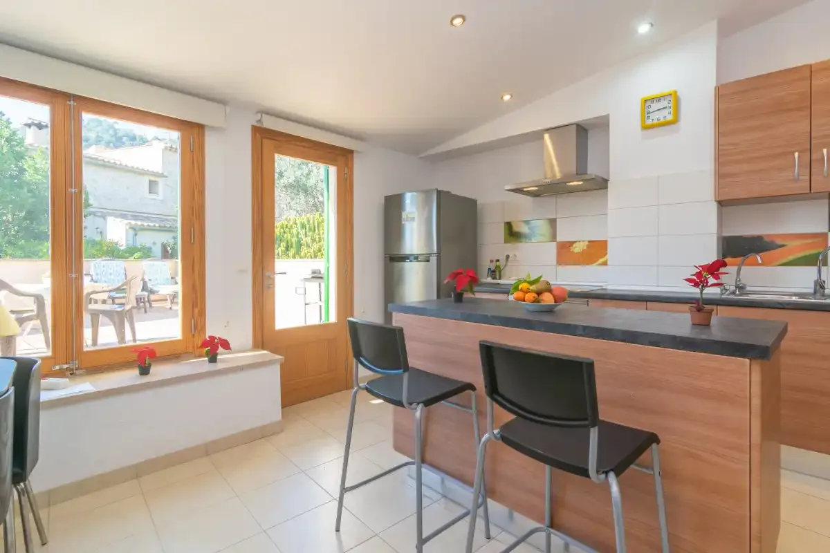 A bright kitchen with a breakfast counter and large windows.
