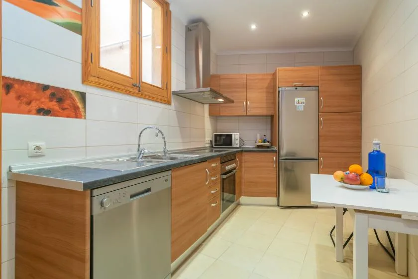 A bright kitchen with wooden cabinets, a refrigerator, and a dining table.