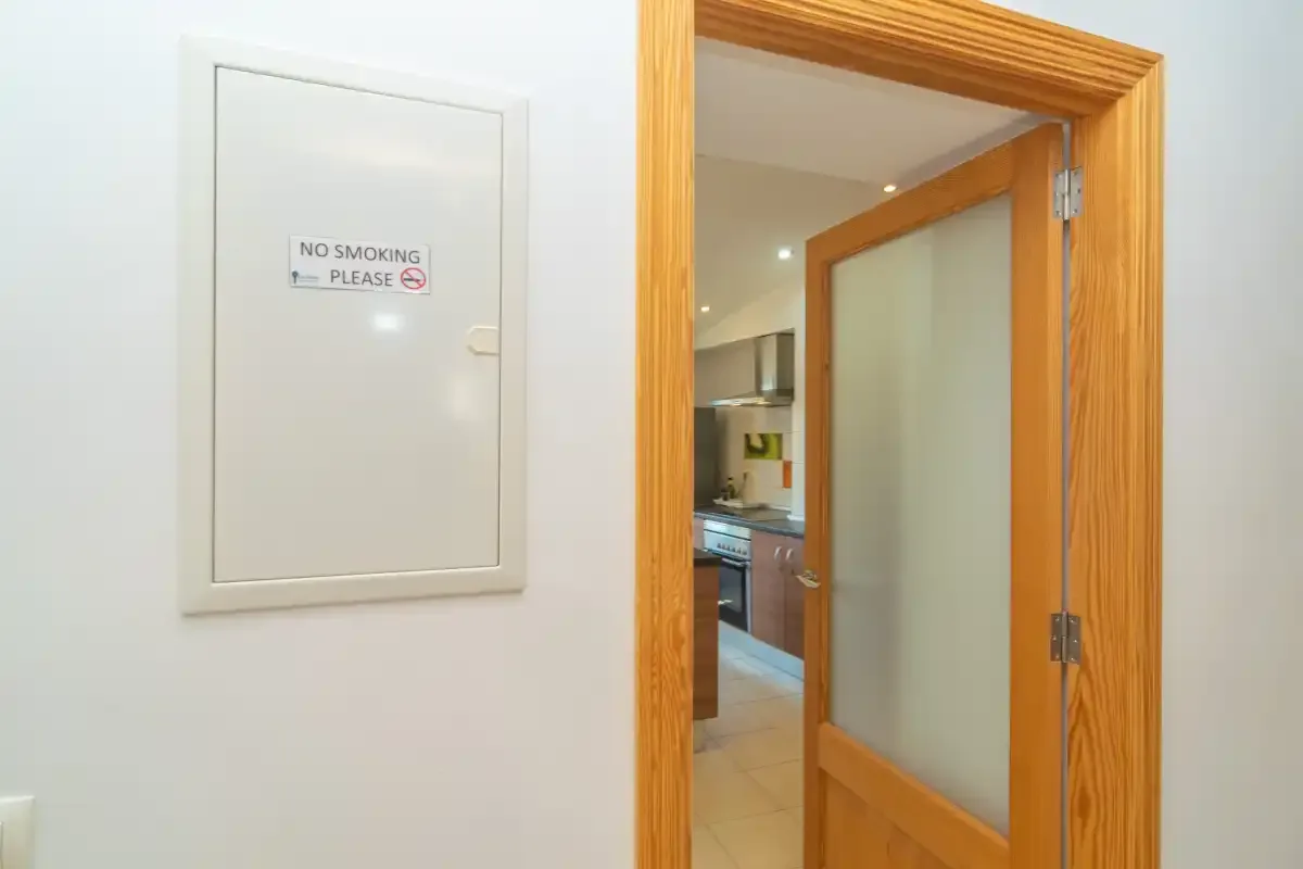 A wooden doorway opens into a kitchen with light-colored flooring.