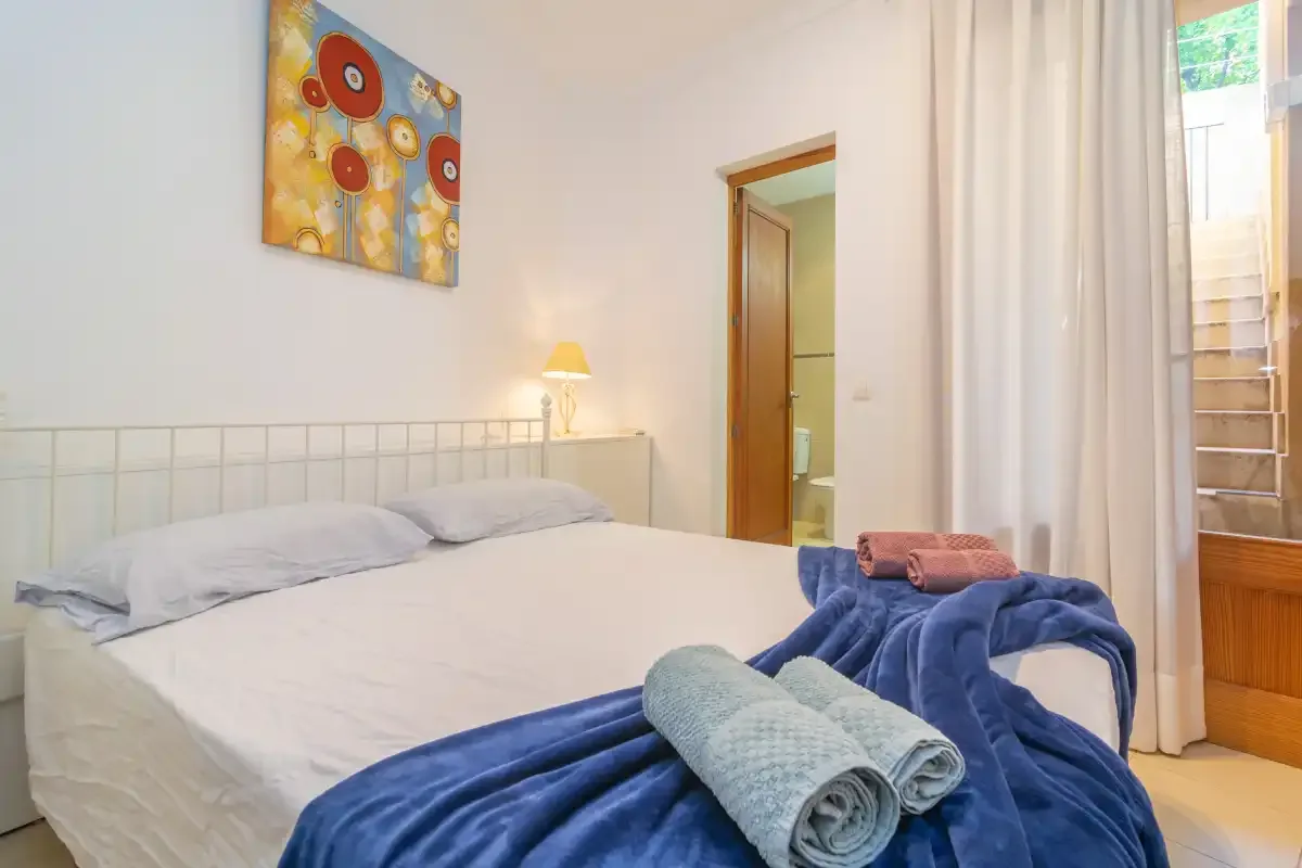 A bedroom with a neatly made bed and folded towels.