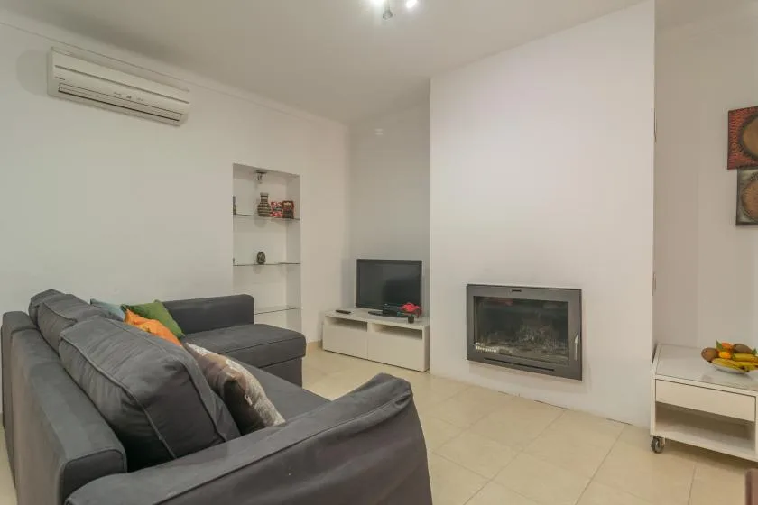 A living room with gray seating, a television, and a fireplace.