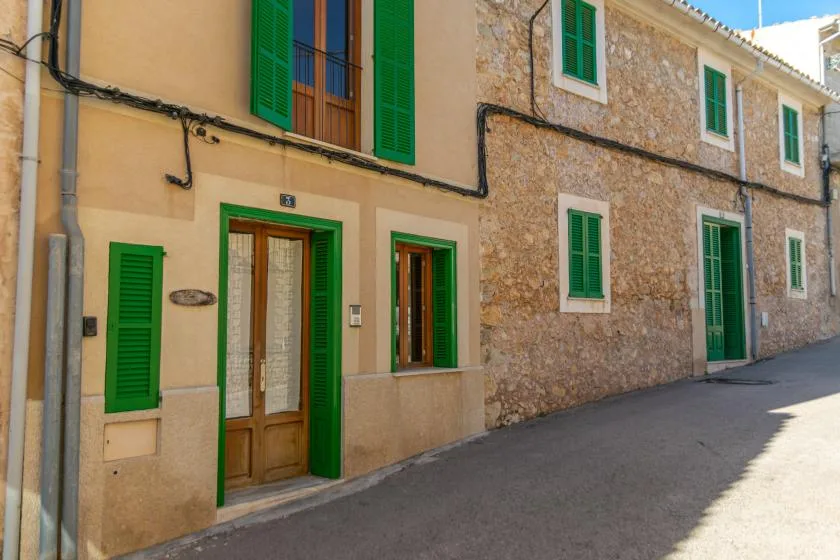 Street view of adjoining houses with green shutters and doors.