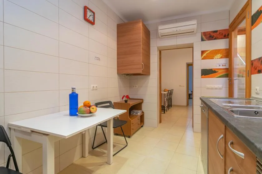 A tiled kitchen with a table, countertop, and cabinets.