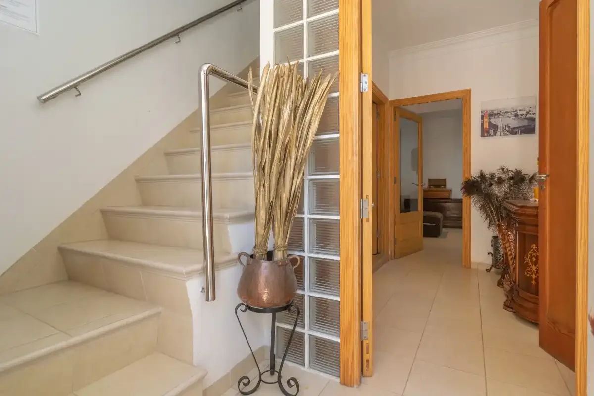An interior hallway with a staircase and an open doorway.