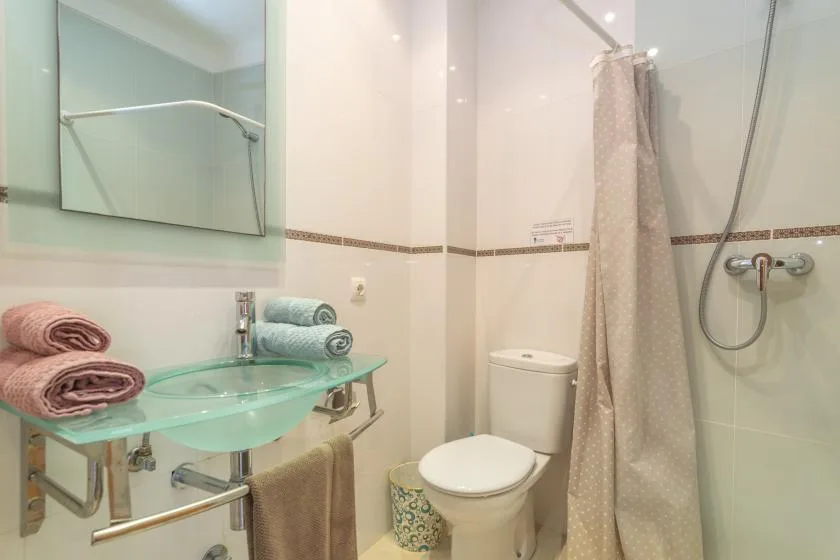 A bathroom with a glass sink, toilet, and shower curtain.