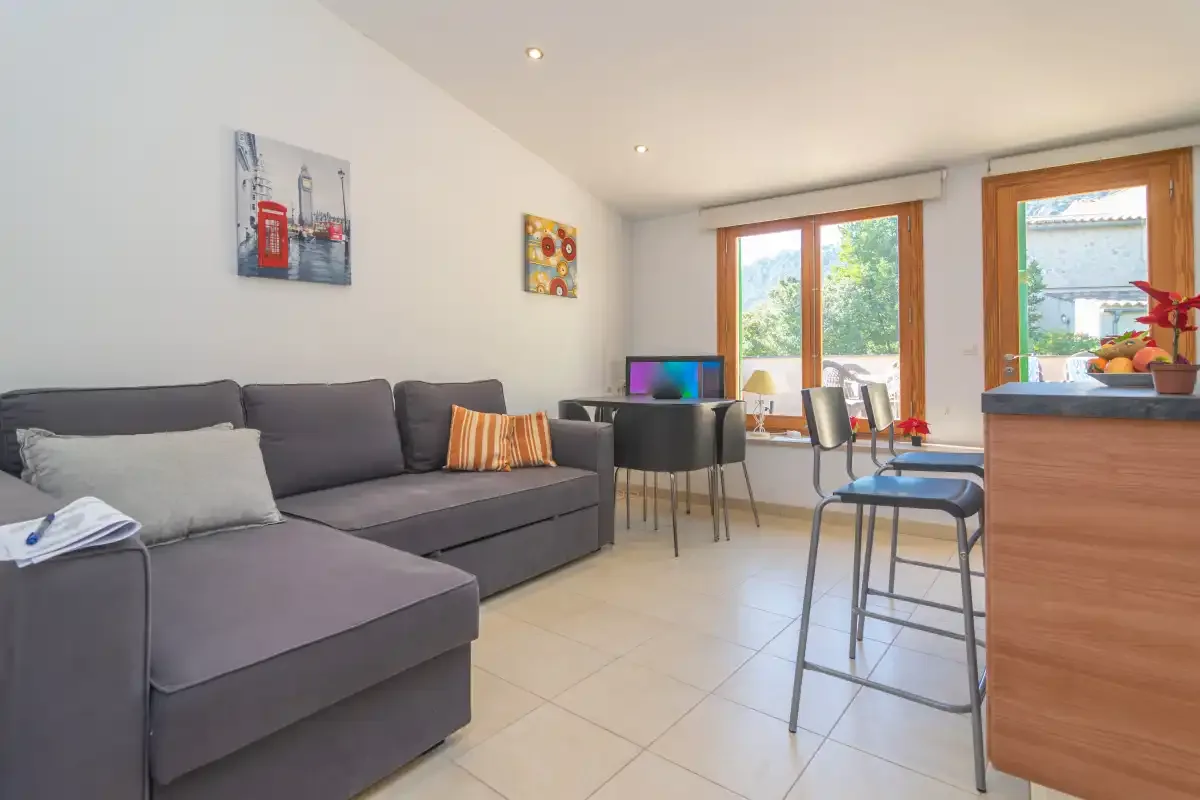 A bright living and dining area with seating and a table beside large windows.