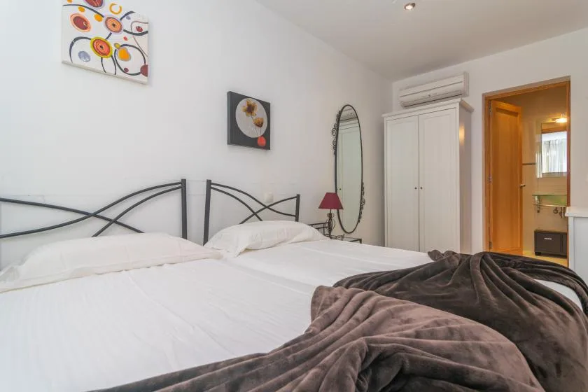 A bedroom with white bedding, dark metal headboards, and a wardrobe.
