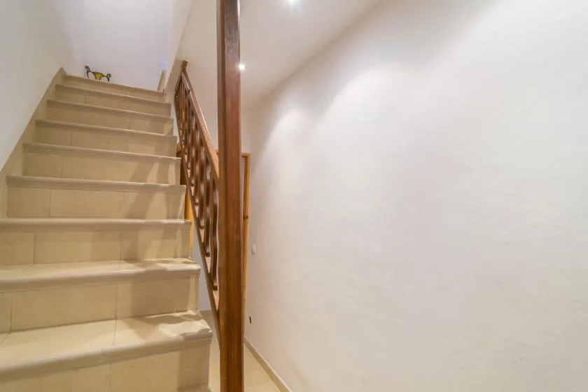 An indoor staircase with beige steps and a wooden railing.