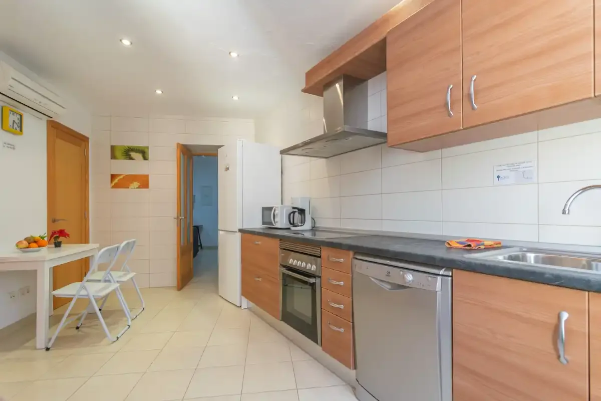 A bright kitchen with wooden cabinets, a countertop, and a small dining table.