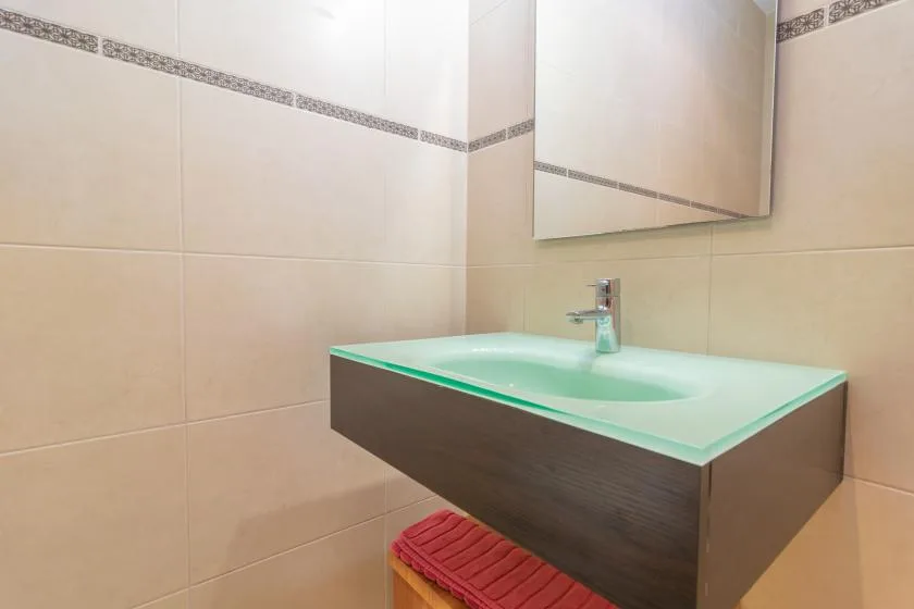 A bathroom vanity with a pale green basin, faucet, and wall mirror.