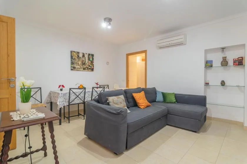 A living room with a gray sectional sofa and a small dining area.