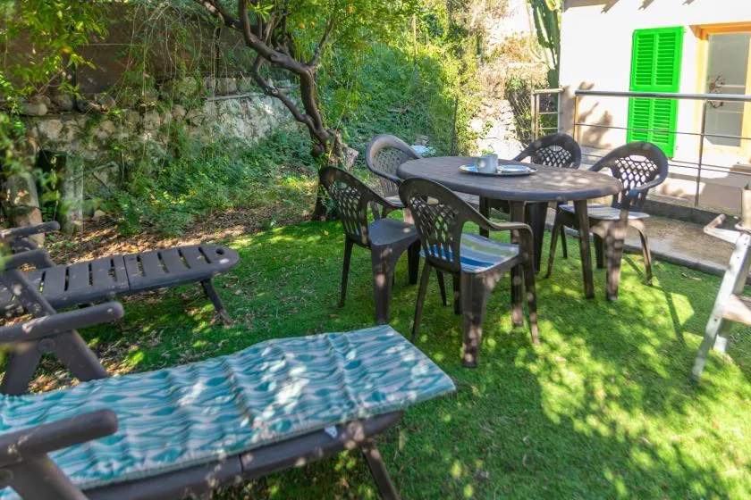 An outdoor dining area with a table and seating sits on a grassy patio.