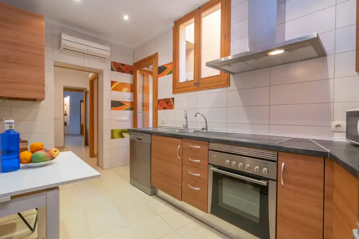 A bright kitchen with wooden cabinets, a countertop, and an oven.