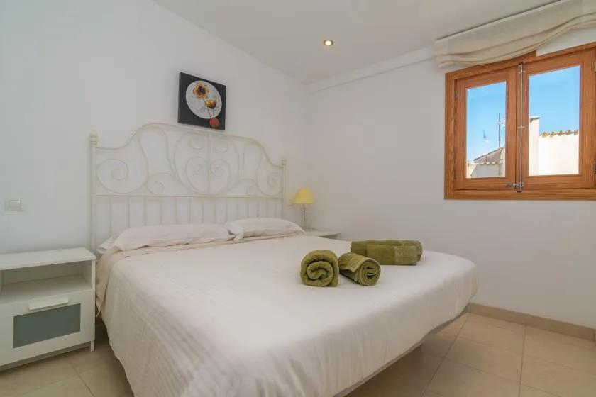 A bright bedroom with a white bed and a window.