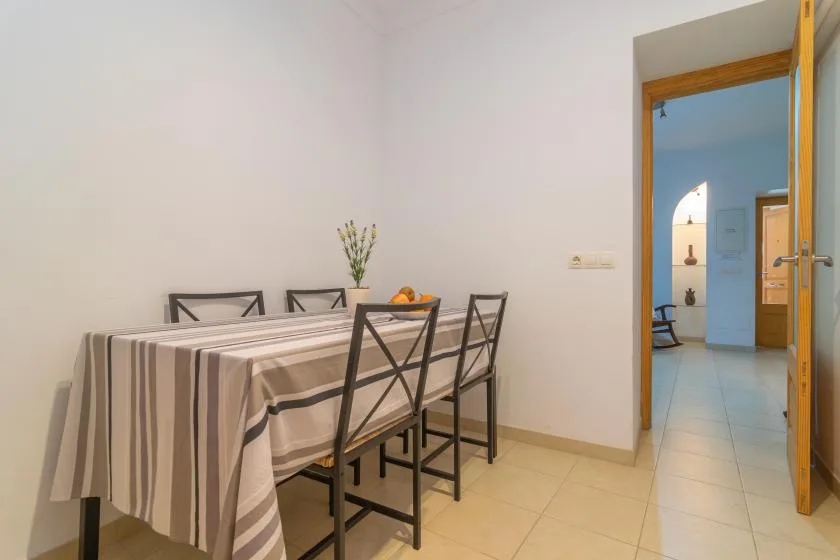 A dining area with a striped tablecloth and dark chairs.