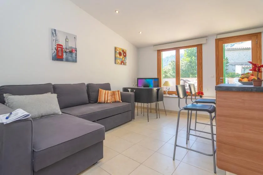A living room with a sectional sofa, dining table, and large windows.