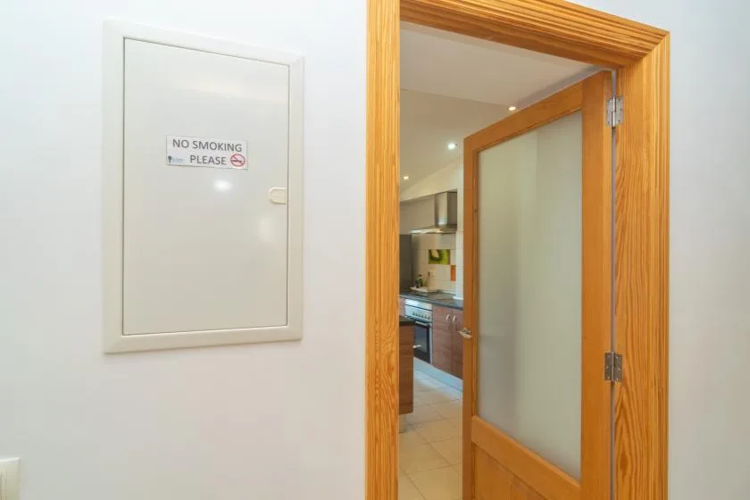 An open wooden doorway leads into a kitchen with counters and cabinets.