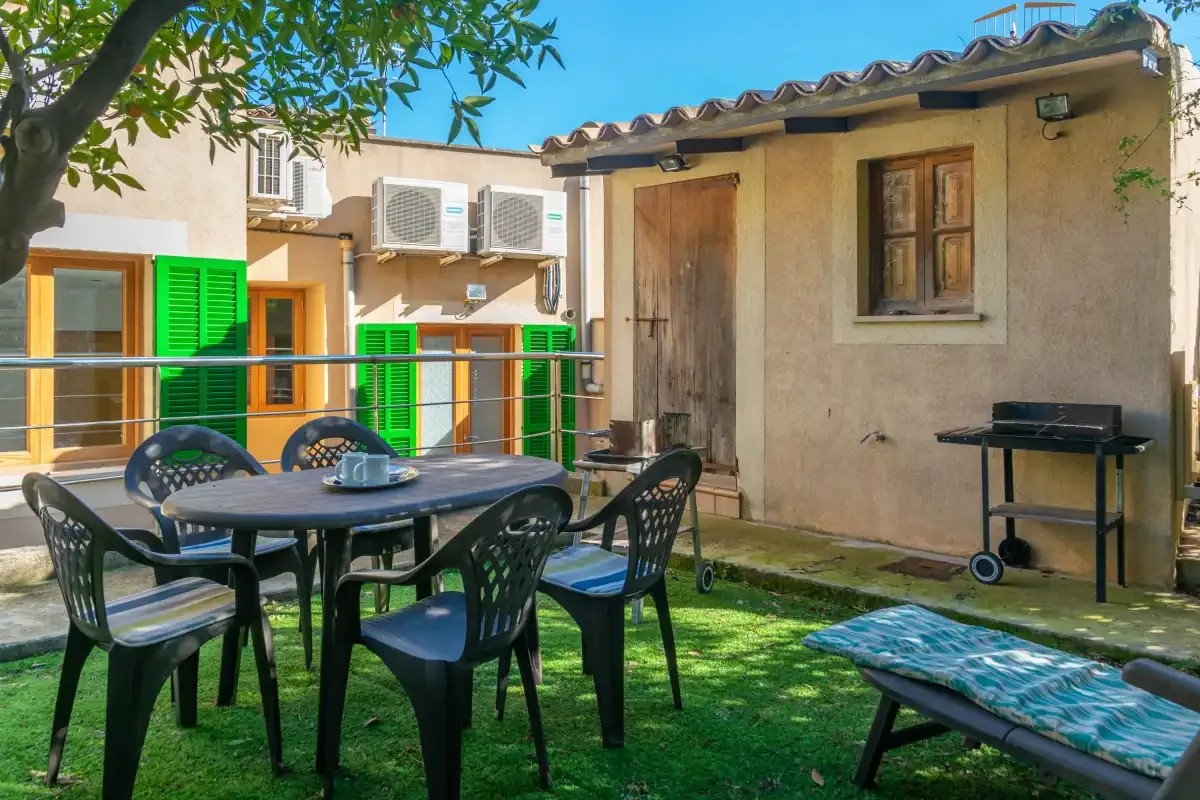 A garden patio with outdoor seating, a barbecue, and a small lawn.