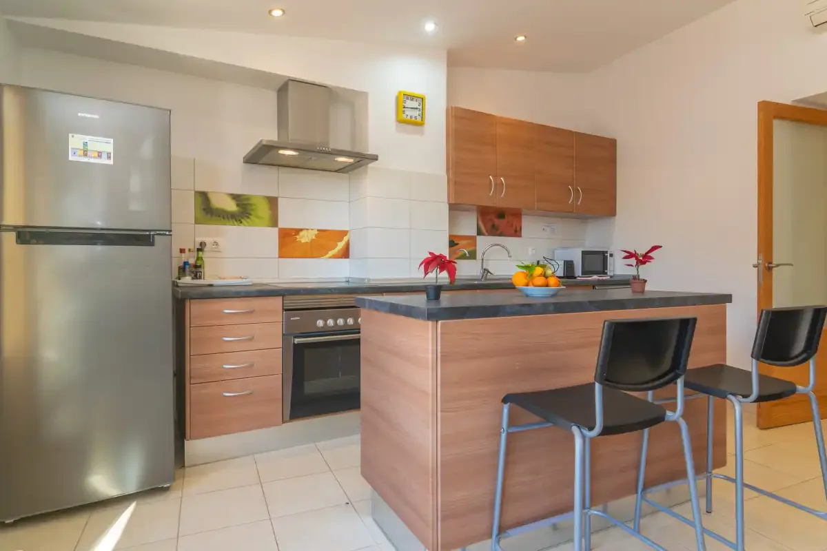 A modern kitchen with a central island, bar seating, and stainless steel appliances.